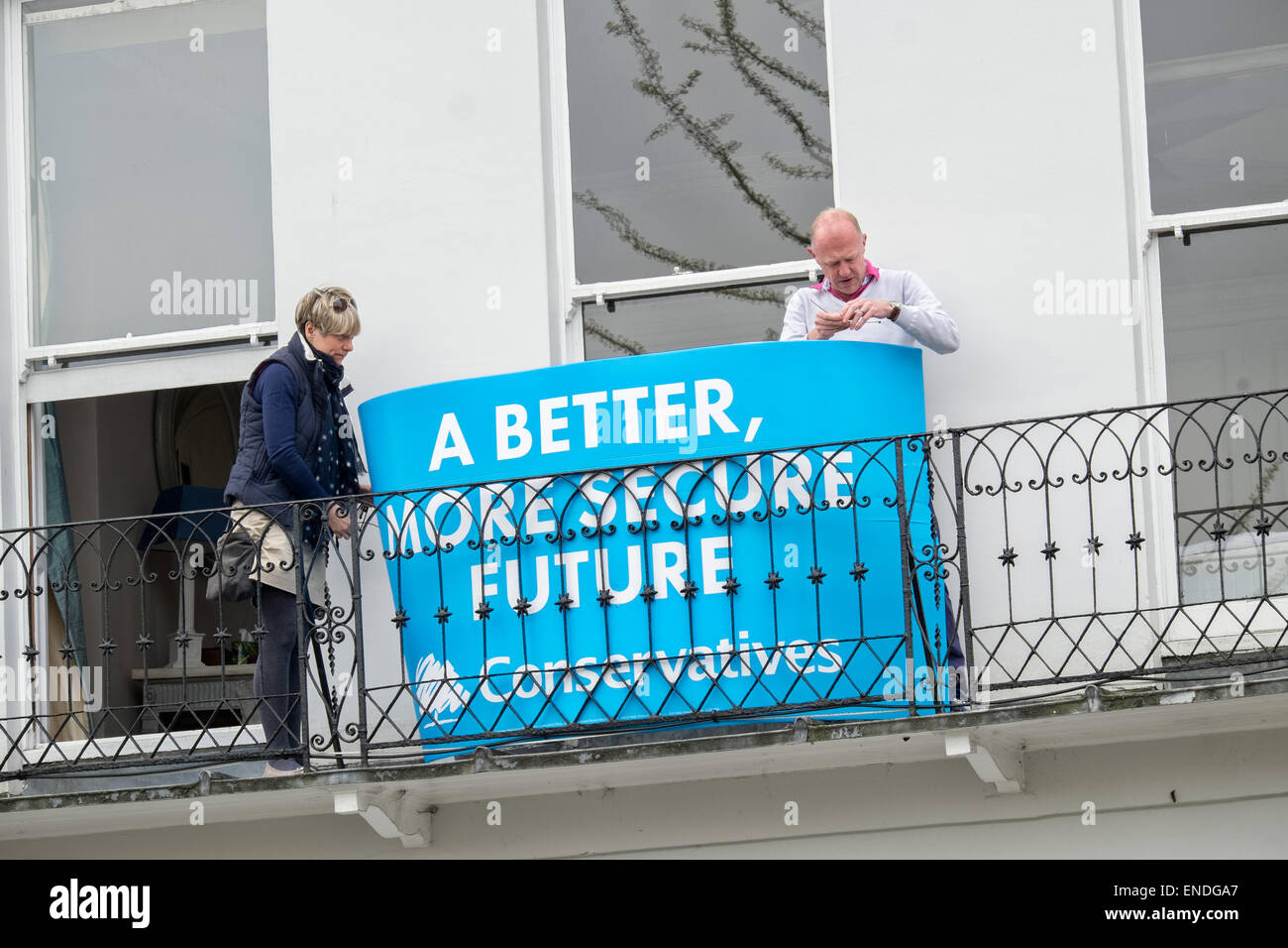 Un par asegurar una bandera electoral del partido conservador a un balcón en la parte exterior de su hogar, REINO UNIDO Foto de stock