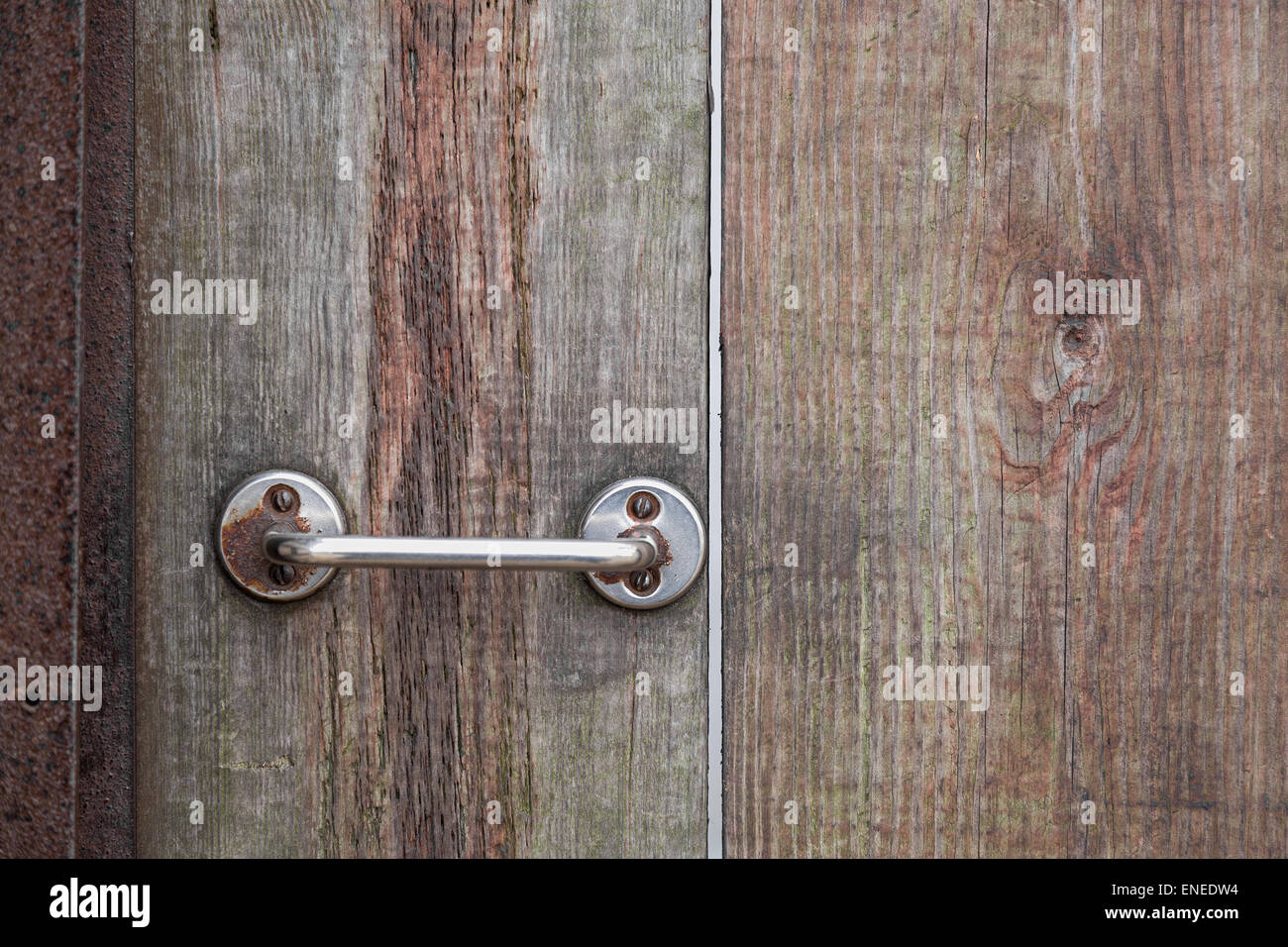 Empuñadura de puerta de metal oxidado sobre fondo de madera Foto de stock