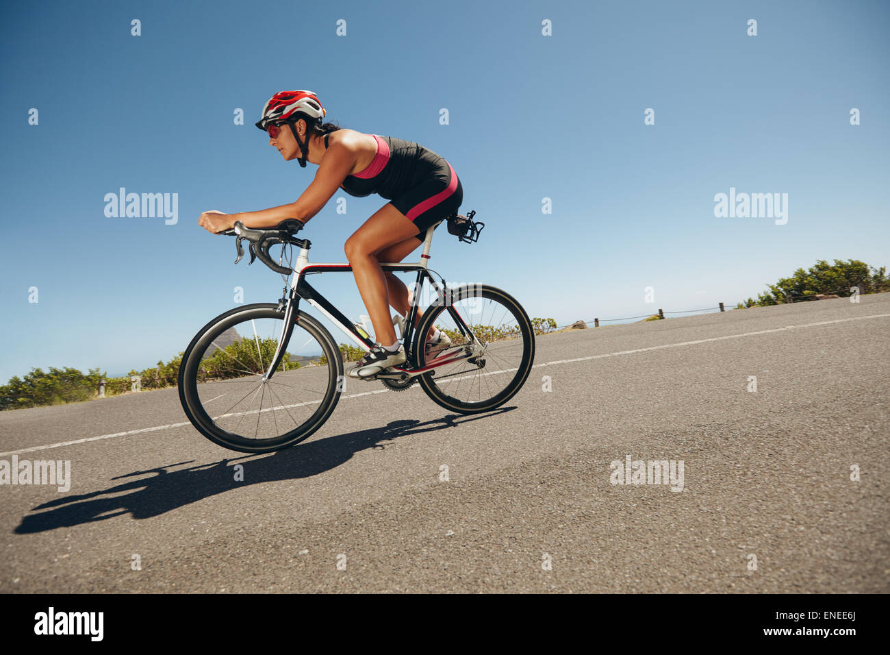 Ciclista femenina en un país por carretera entrenamiento para la competencia. Mujer joven montando bicicleta colina abajo. Foto de stock