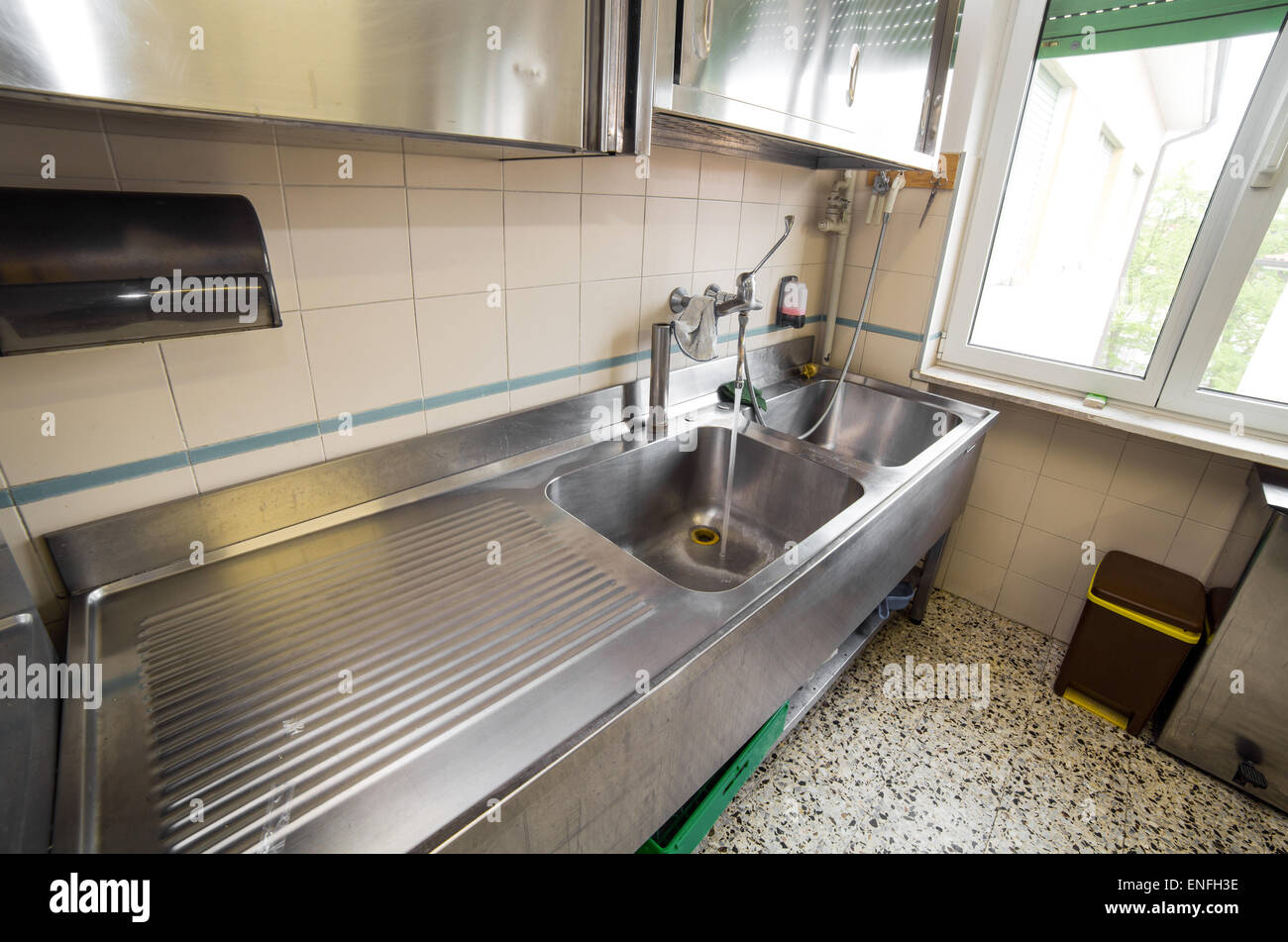 Enorme fregadero cocina industrial de acero inoxidable con grifo abierto  Fotografía de stock - Alamy