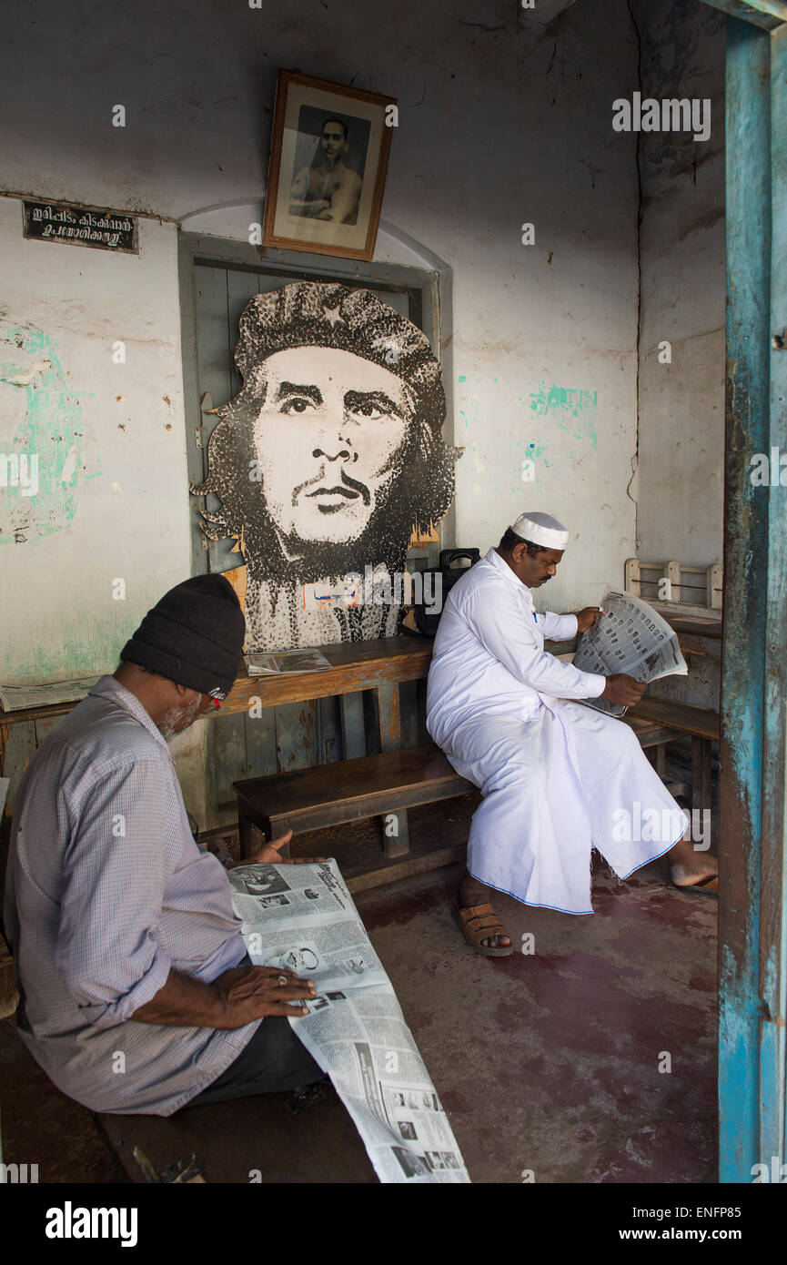 Dos hombres leyendo periódicos en una habitación con un retrato de Che Guevara, Fort Cochin, Kochi, Kerala, India Foto de stock