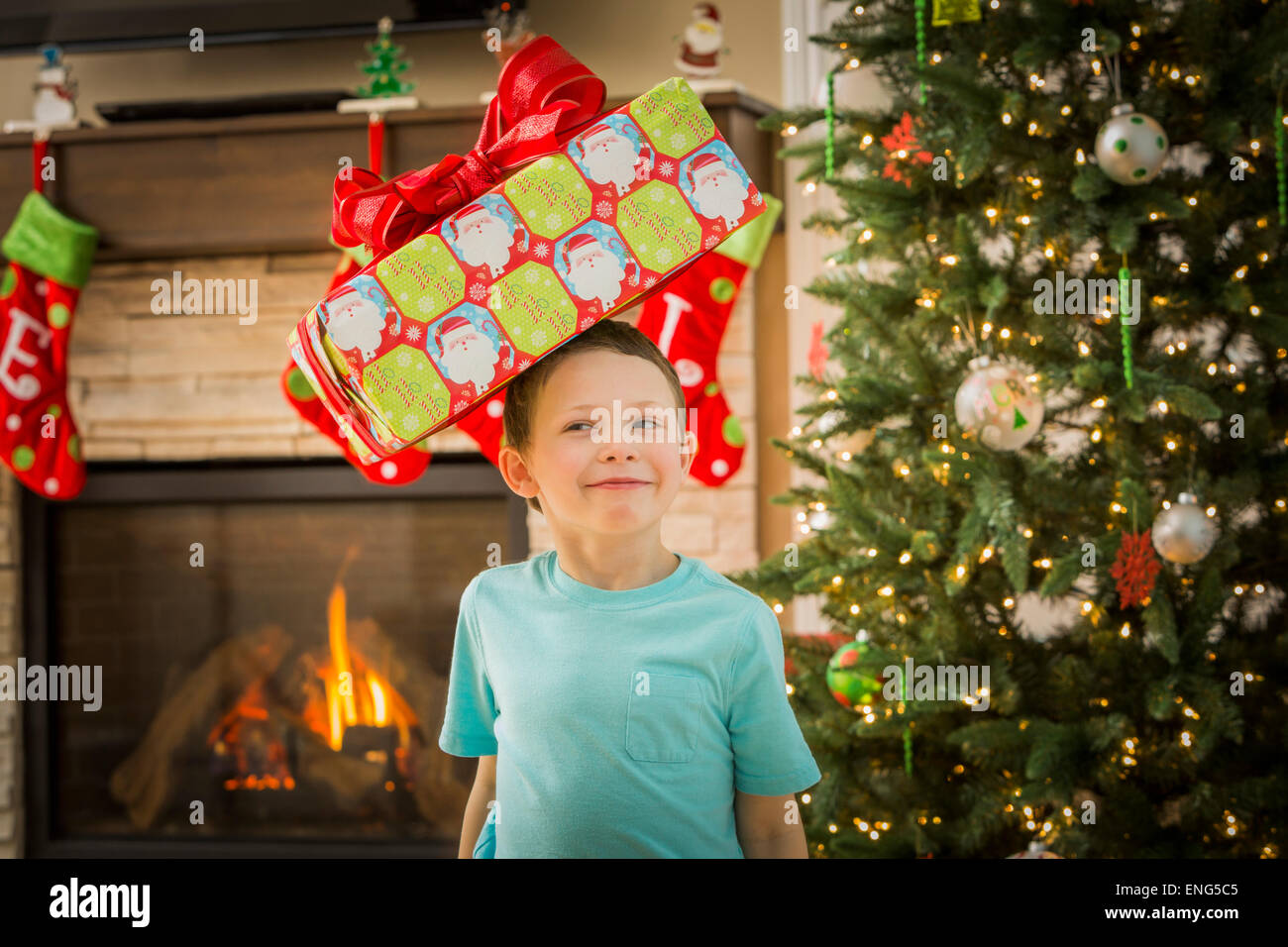 Muchacho caucásico equilibrando su regalo de Navidad en la cabeza. Foto de stock