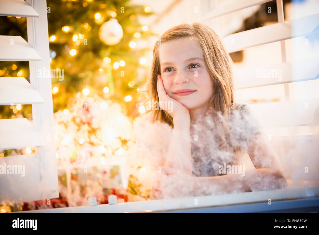 Chica caucásica asomándose por la ventana en Navidad Foto de stock