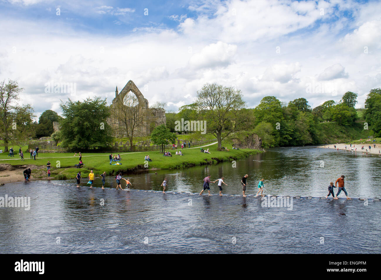 Los turistas y visitantes que cruzan la frontera de Stepping Stones en frente de Bolton Abbey priorato. Bolton Abbey, Wharfedale, Reino Unido. Foto de stock