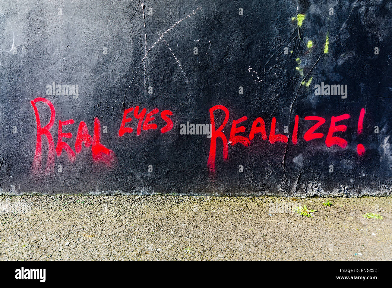 Graffiti en una pared diciendo 'Real ojos. Cuenta!". Foto de stock