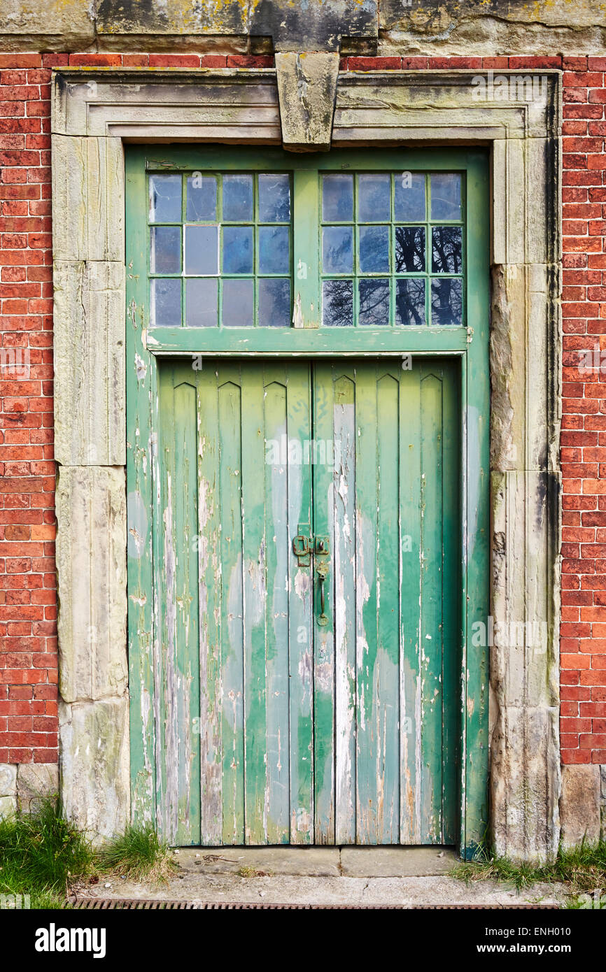Puerta de madera verde con piedra surround en el antiguo bloque estable en Calke Abbey, Derbyshire, Inglaterra, Reino Unido. Foto de stock