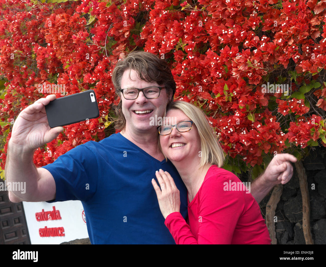 'SELFIE' Una atractiva pareja que se divierte de vacaciones tomando una foto 'selfie' fuera de la atracción de vacaciones en su aplicación de cámara para iPhone Foto de stock