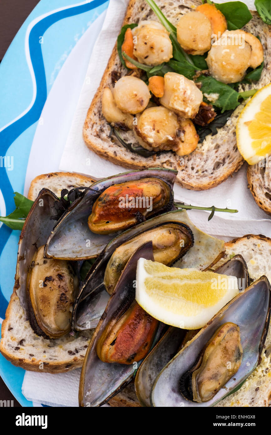 Churrasco de vieiras y mejillones de labios verdes sobre el pan en una choza de comida al aire libre en la playa en Kaikoura, Nueva Zelanda Foto de stock
