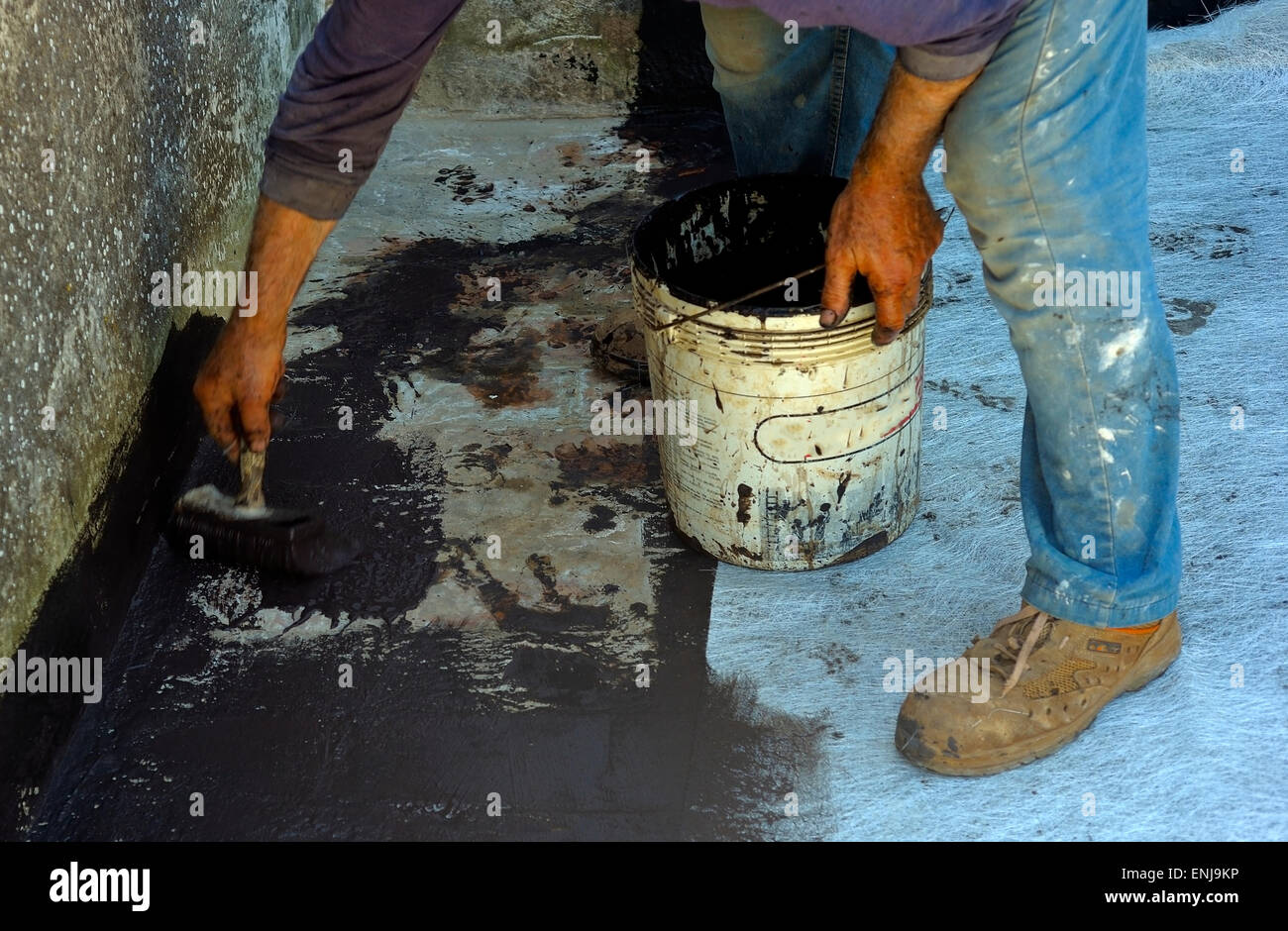 Trabajador posando con revestimiento bituminoso pincel líquido sobre lámina de fibra de vidrio Foto de stock