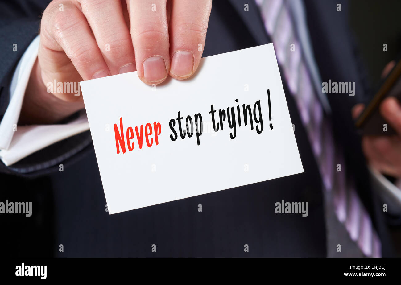 Un empresario sosteniendo una tarjeta con las palabras, nunca dejar de intentar. Foto de stock