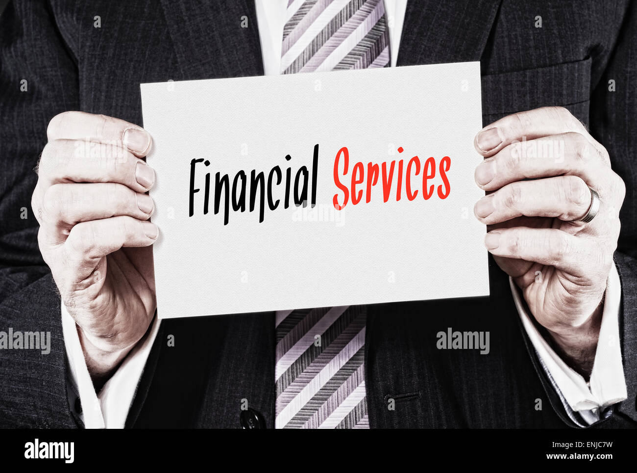 Un empresario sosteniendo una tarjeta con las palabras, los servicios financieros, escrito en ella. Foto de stock