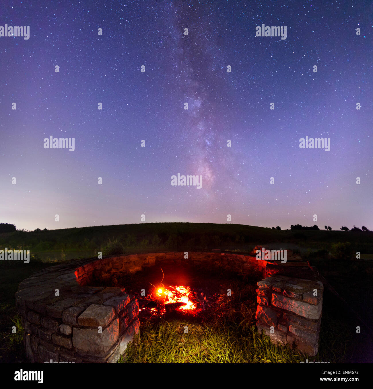 Pozo de fuego en el campo, con cielo estrellado en el fondo Foto de stock