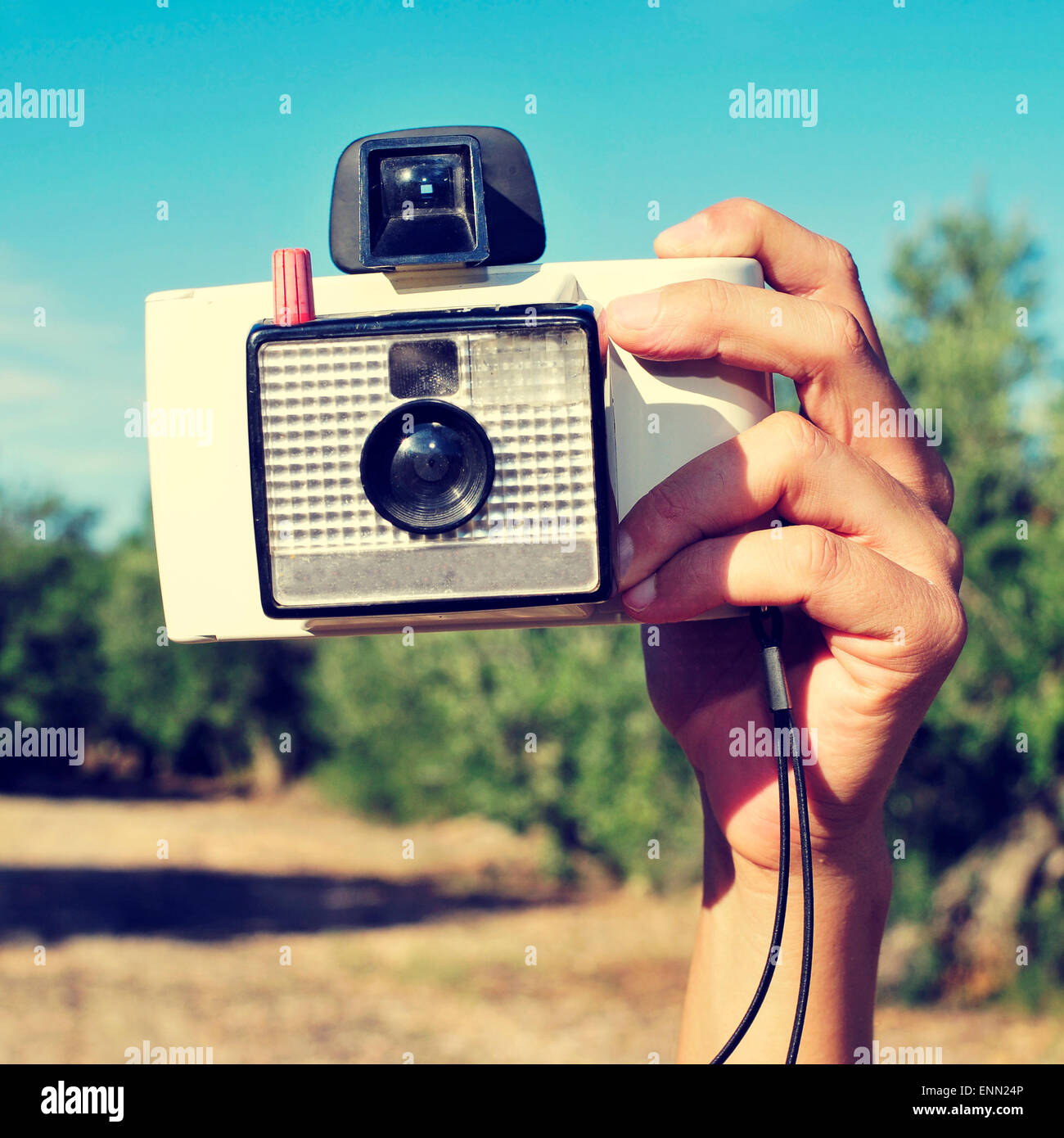 Primer plano de la mano de un joven de tomar una fotografía con una antigua cámara  instantánea, en un paisaje natural, con un efecto retro Fotografía de stock  - Alamy