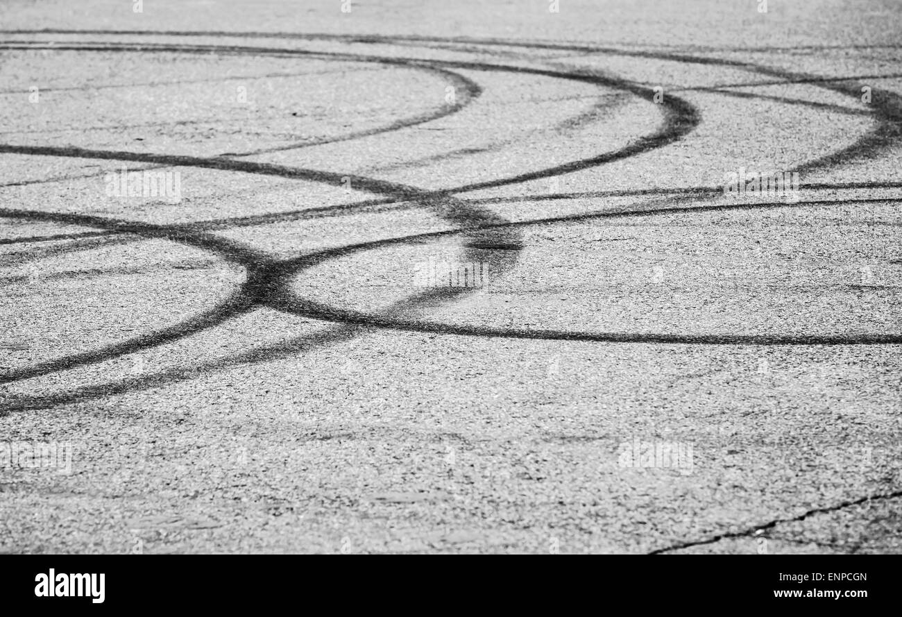 Transporte abstractos con fondo gris oscuro las huellas de los neumáticos sobre el asfalto, el enfoque selectivo con poca DOF Foto de stock