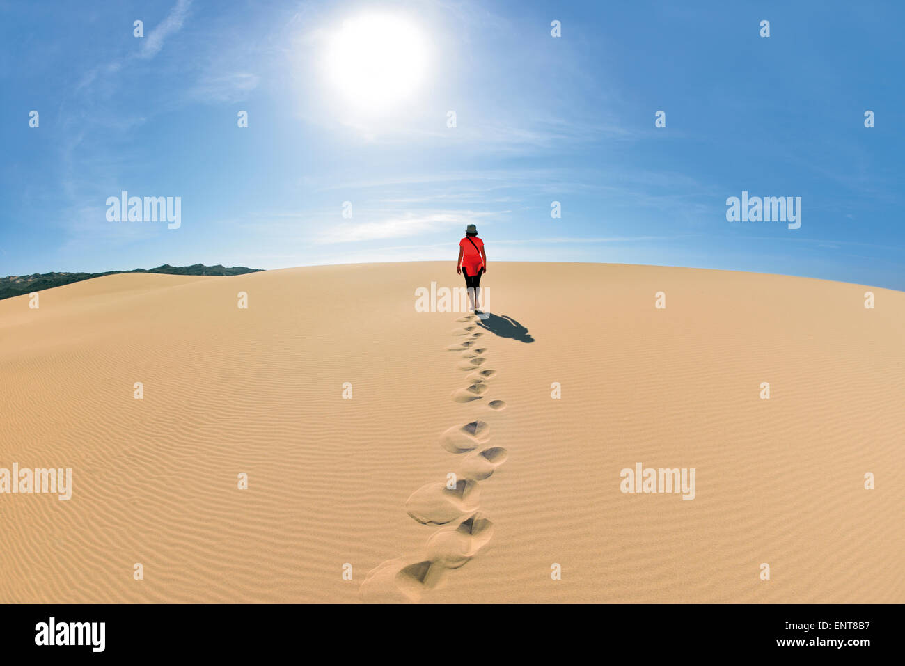 Portugal, Algarve: mujer caminando sobre una duna de arena en la dirección del sol Foto de stock