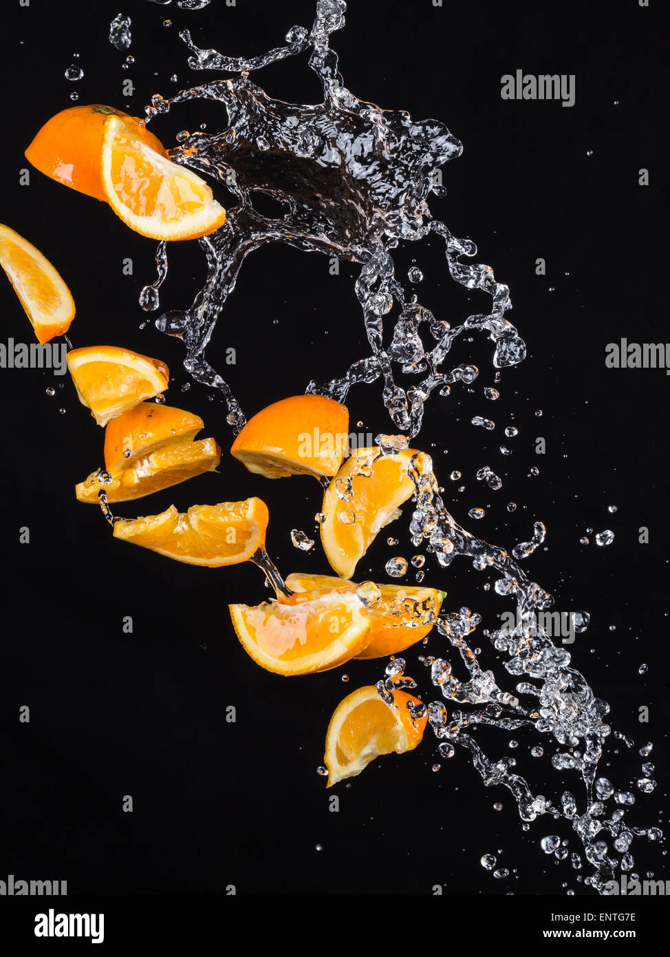 Fruta naranja con salpicaduras de agua sobre fondo negro Foto de stock