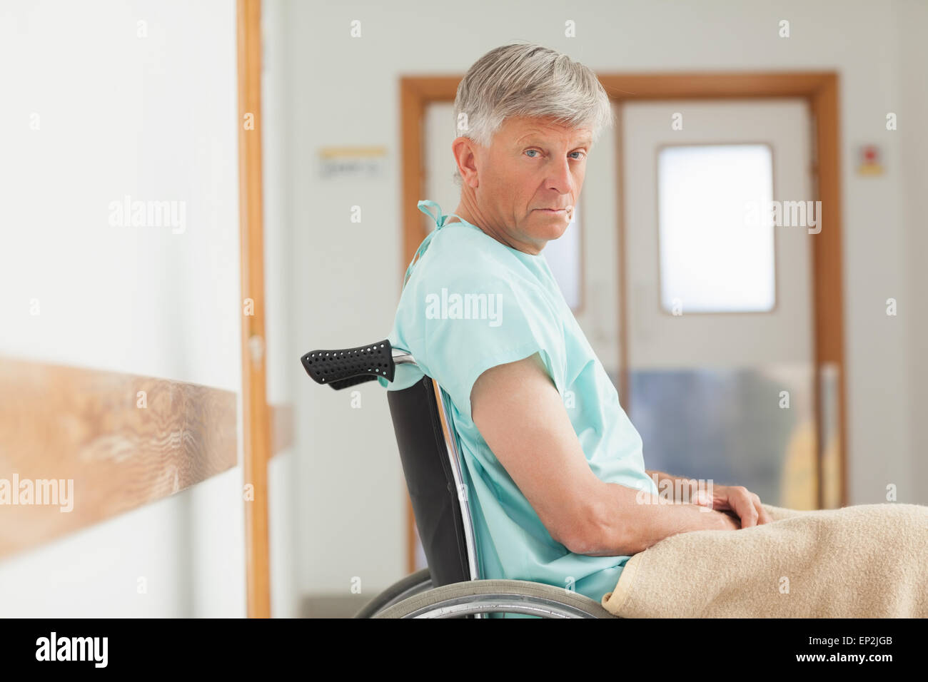 Hombre sentado en una silla de ruedas mientras mirando a la cámara Foto de stock