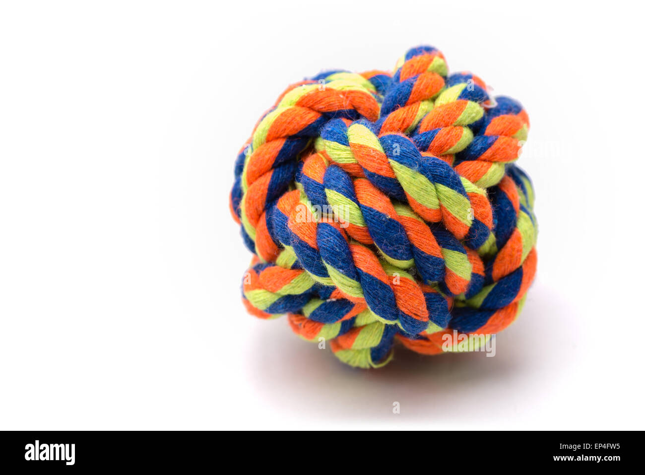 Una bola muy colorida hecha de cuerda atada en un nudo del puño del mono usado para un perro de juguete. Foto de stock