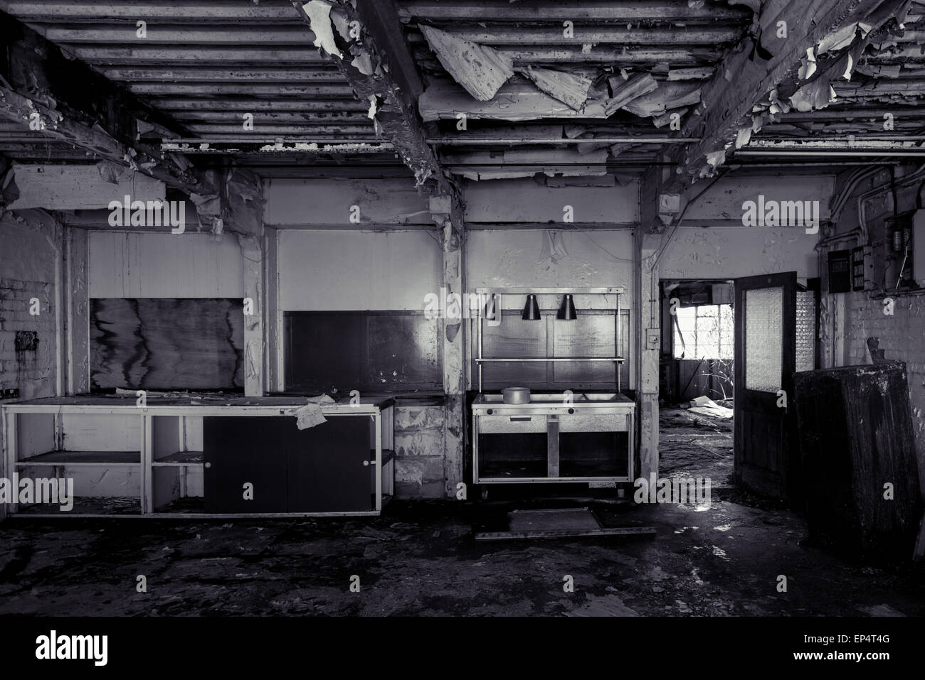 Blanco y negro abandonados abandonados, cocina con techo arruinado severamente Foto de stock