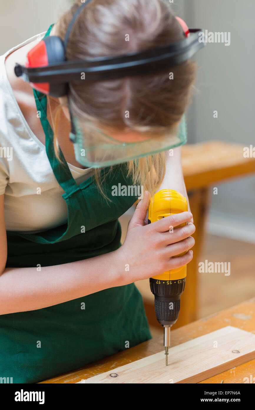 Taladrar un orificio de estudiante en una placa de madera en el workbench Foto de stock