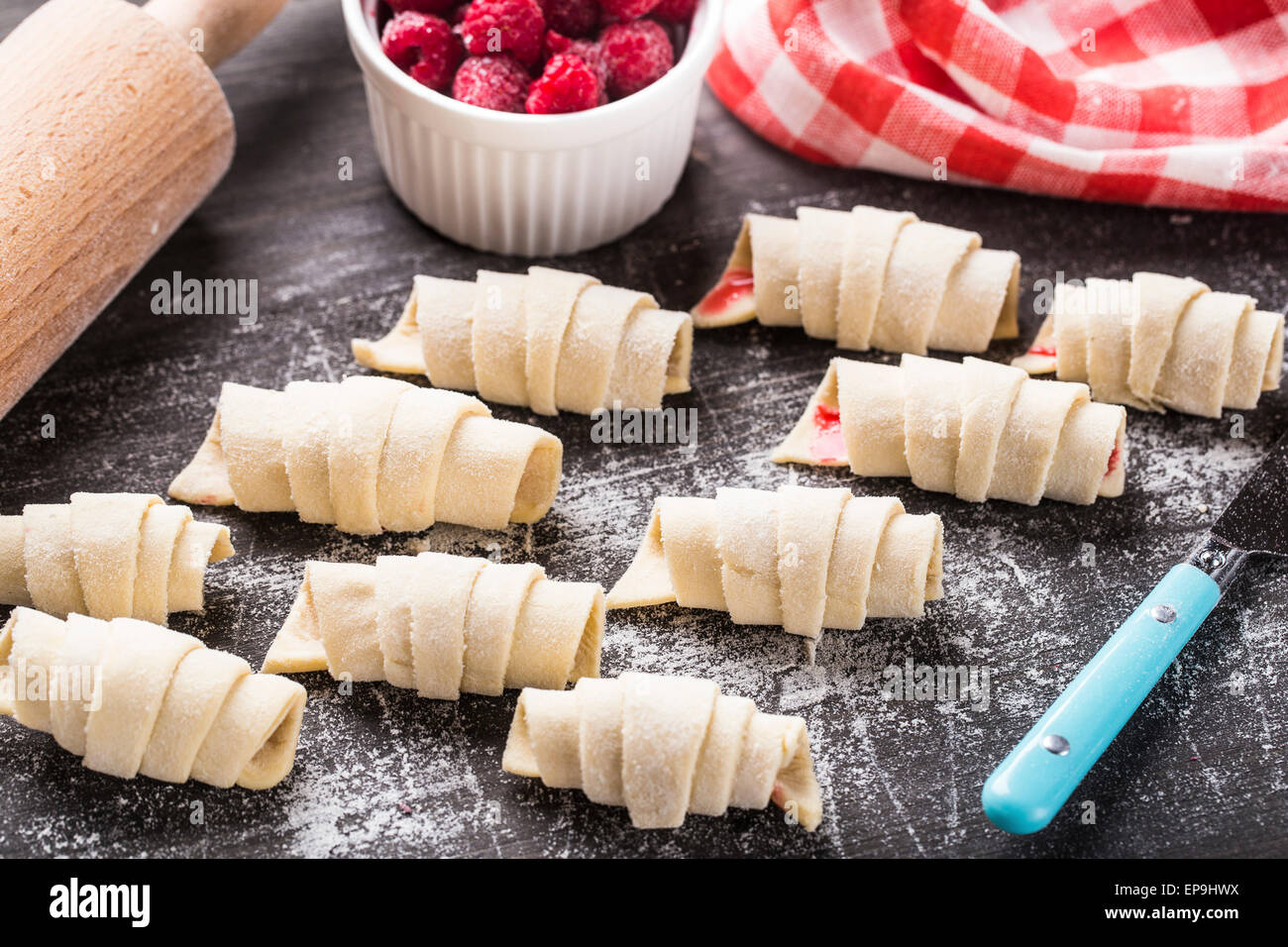 Hacer croissants caseros rellenos con frambuesas dulces Foto de stock