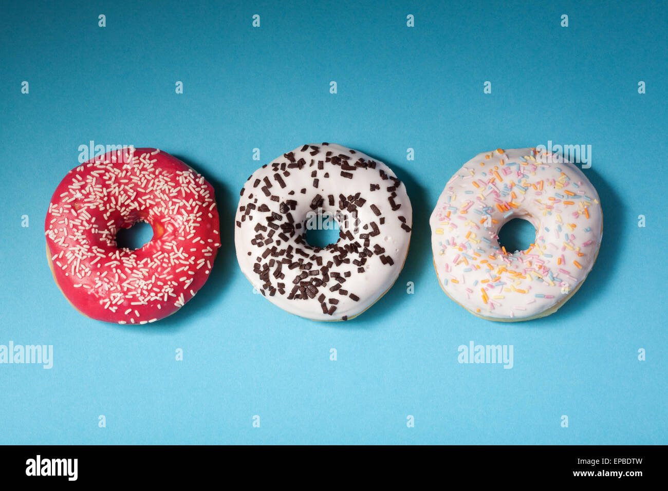Vista superior de tres donuts aislado en azul Foto de stock