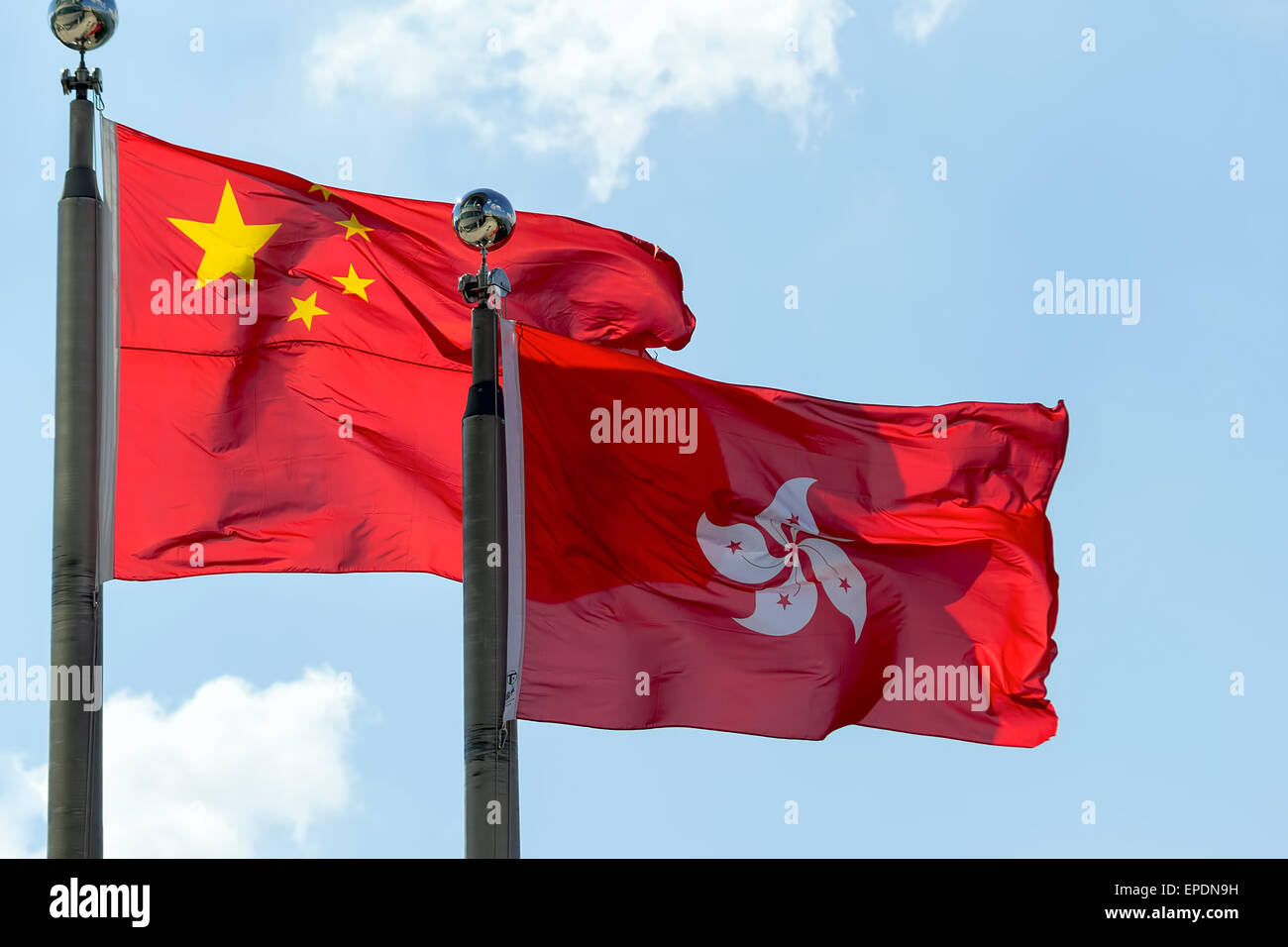 Hong Kong y la República Popular de China banderas ondeando al lado contra el cielo azul Foto de stock