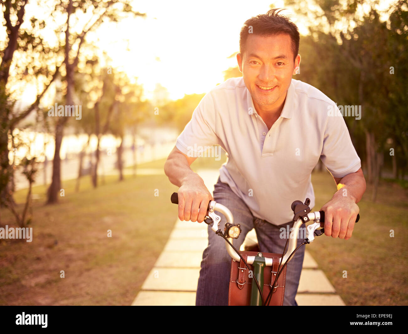 Hombre asiático disfrutando de un paseo en bicicleta en el parque Foto de stock