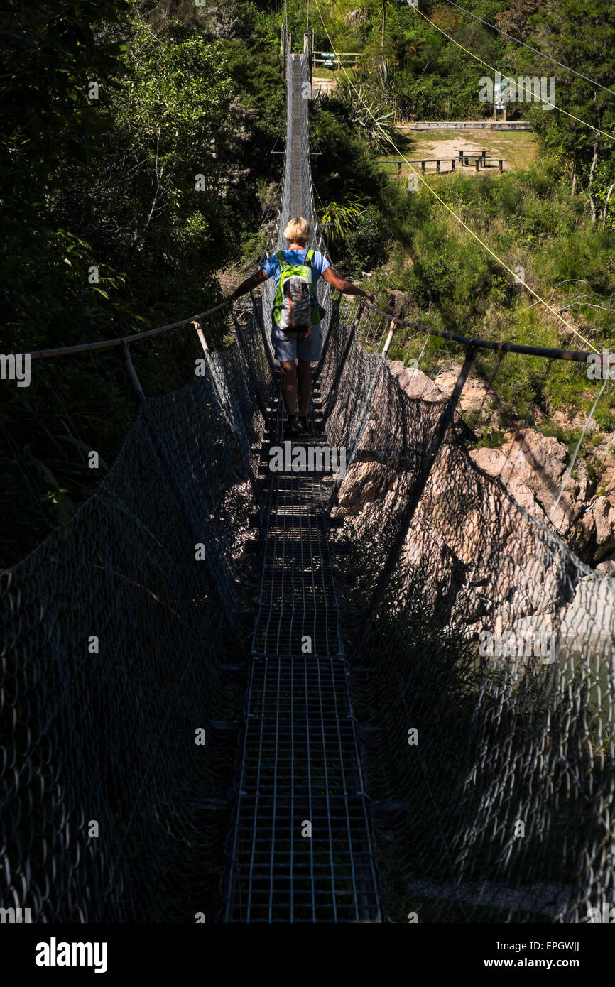 Mujer cruzando Buller Gorge swingbridge, Nueva Zelanda. Foto de stock