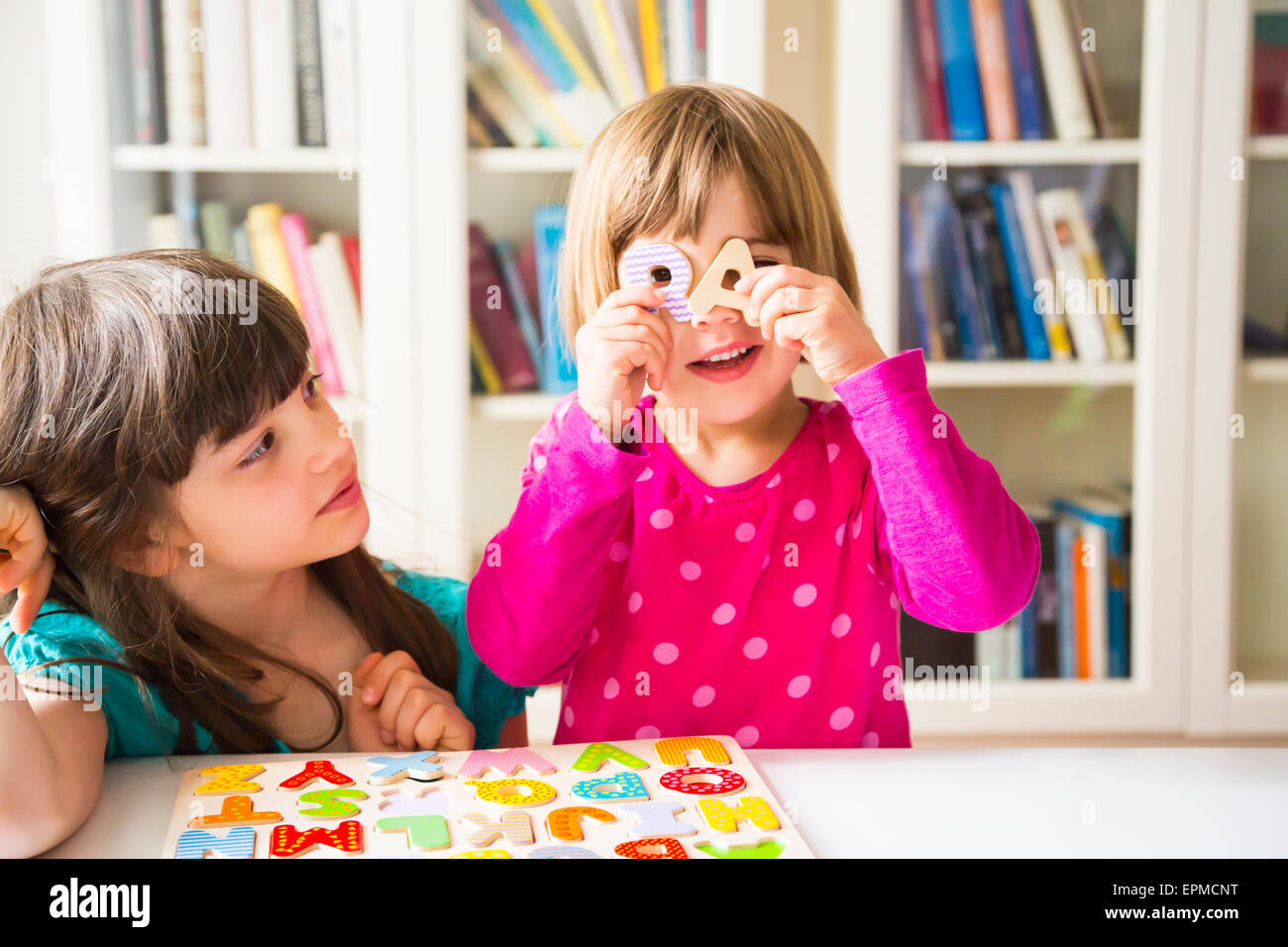 Dos hermanas con un alfabeto de madera puzzle Foto de stock
