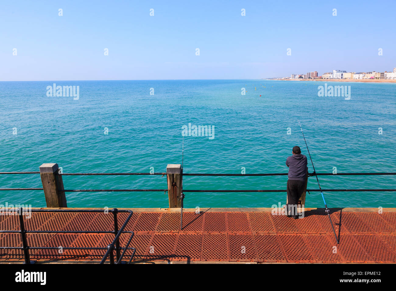 Casualmente el hombre inclinado sobre barandillas de Worthing Pier pesca Foto de stock