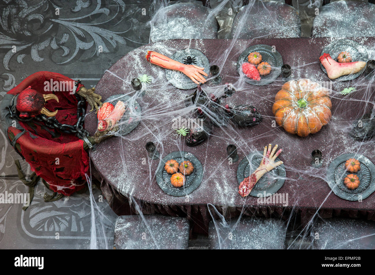 Cena con partes del cuerpo humano sobre la mesa, adornado con telas de araña Foto de stock