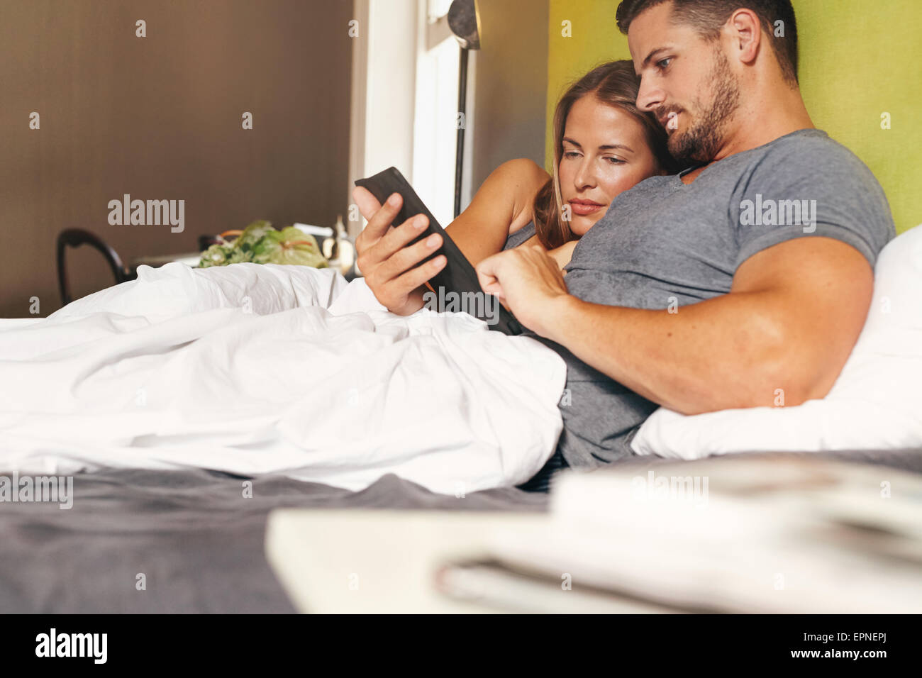 Foto de una pareja joven acostado en la cama y el uso de una tableta digital junto a la mañana Foto de stock