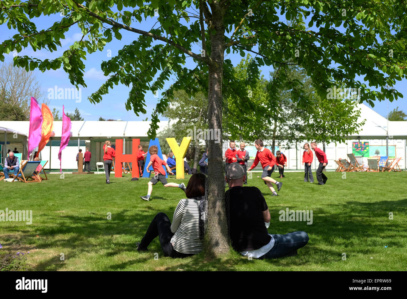 Hay Festival, Powys, Gales - el día de la apertura para el 2015 Festival de heno en el sol. Un par ver como los niños de la escuela disfruta de un recorrido alrededor de la gigantesca heno firmar el día 1 del Hay Festival. Foto de stock