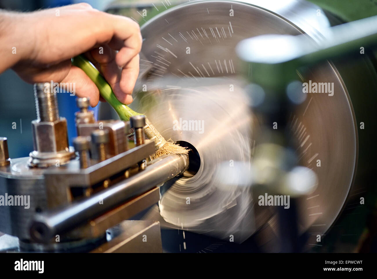 El hombre colocando aceite lubricante en un torno en un taller industrial o de ingeniería Foto de stock