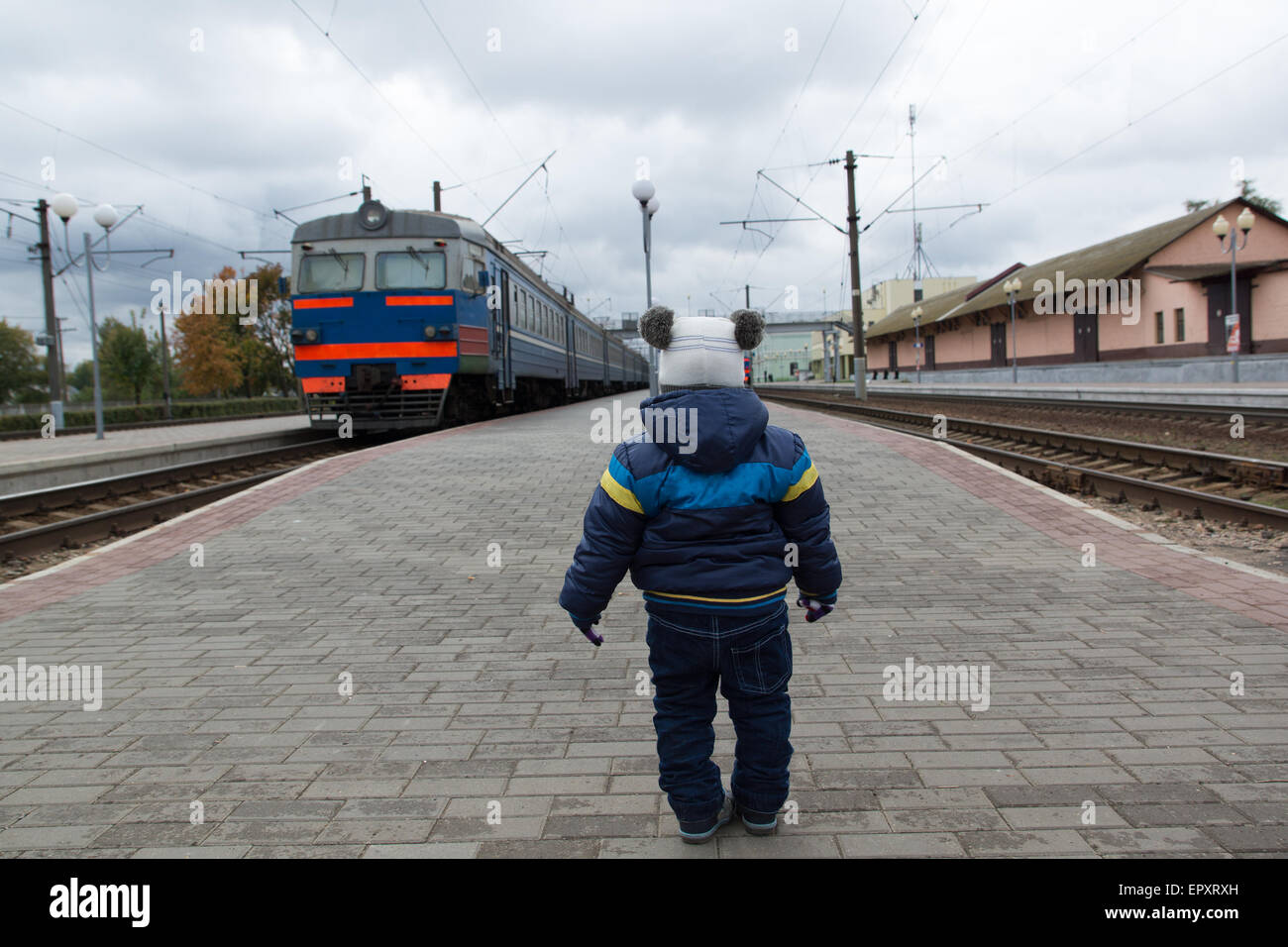 Niño parado en la plataforma y espera después de la partida de tren Foto de stock