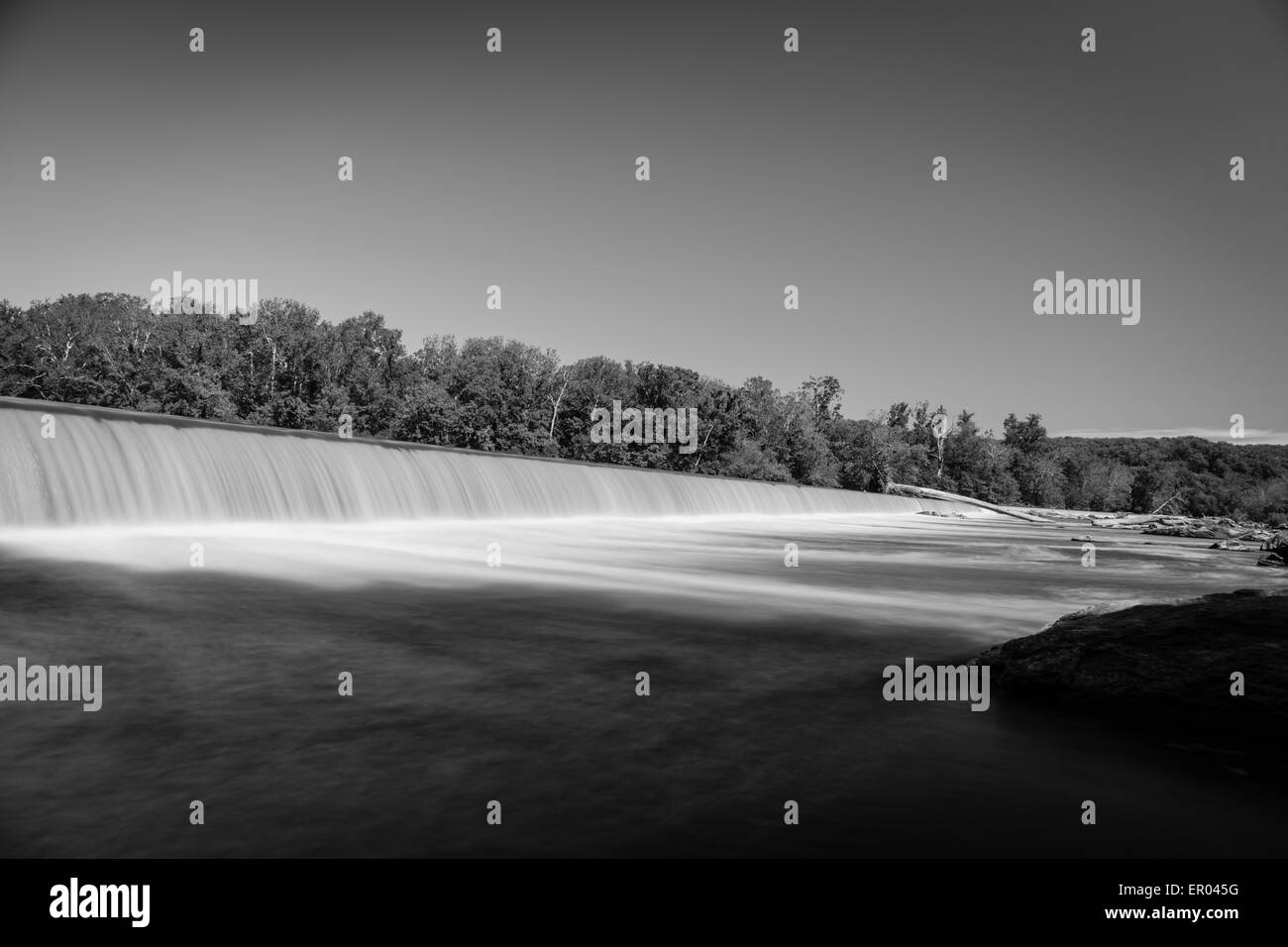 La larga exposición de sedosa de vertido del agua sobre el hombre hizo presa en blanco y negro Foto de stock