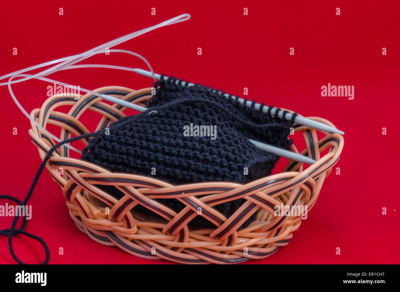 Hecho a mano y tejido negro con aguja de tejer en una cesta Foto de stock