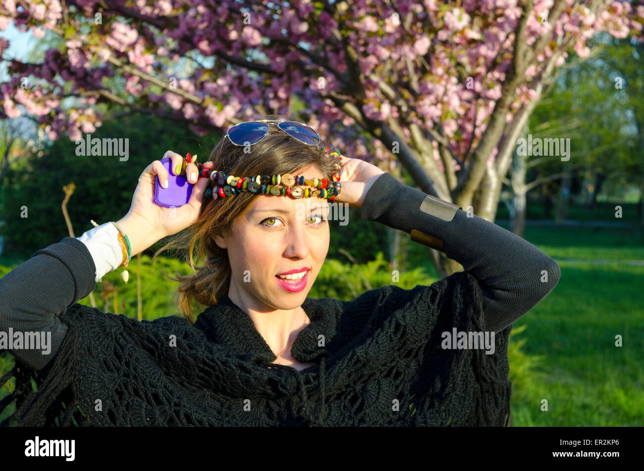 Chica Hippy posando con coloridos collares alrededor de su cabeza al aire libre Foto de stock