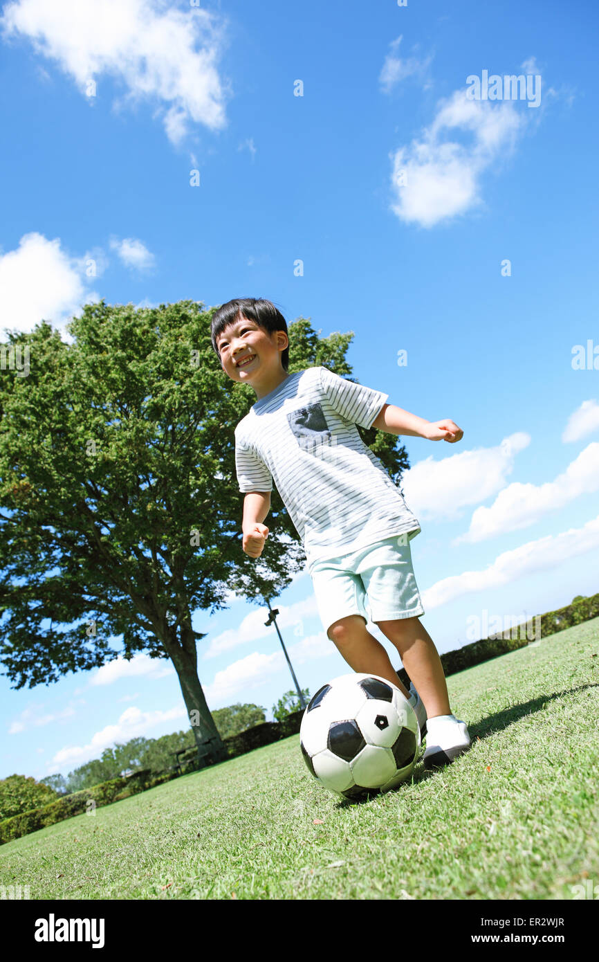 Joven japonés jugando fútbol en un parque de la ciudad Fotografía de