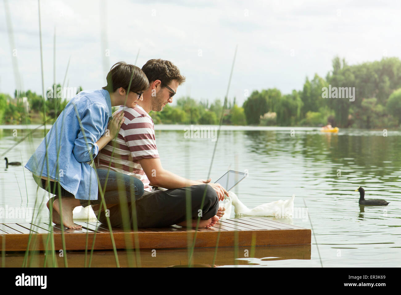 Pareja utilizando equipo portátil en el dock Foto de stock