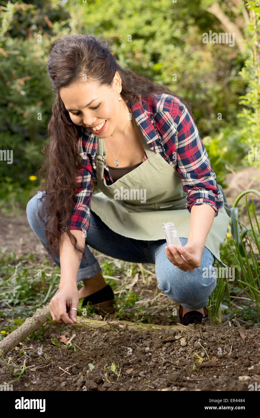 Mujer joven sembrando semillas en el jardín. Foto de stock