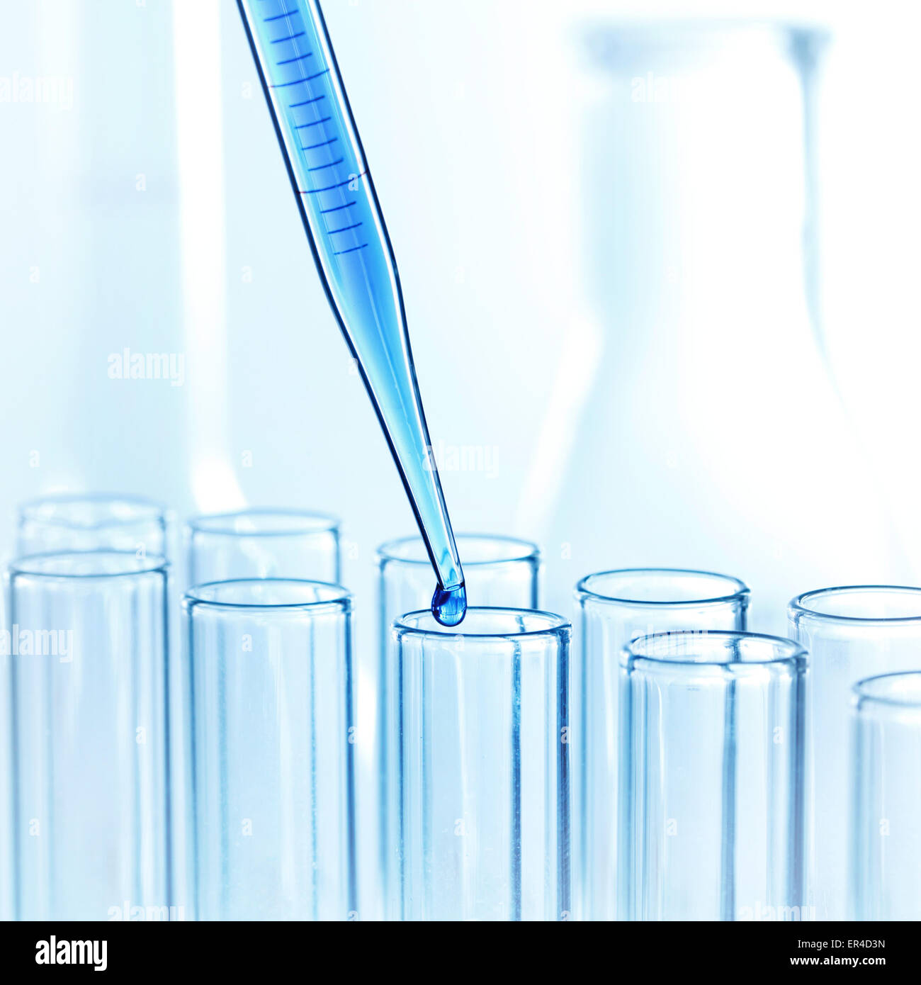 Degenerar En realidad progresivo Pipeta de laboratorio con una gota de líquido en tubos de ensayo de vidrio  en un laboratorio de investigación científica Fotografía de stock - Alamy