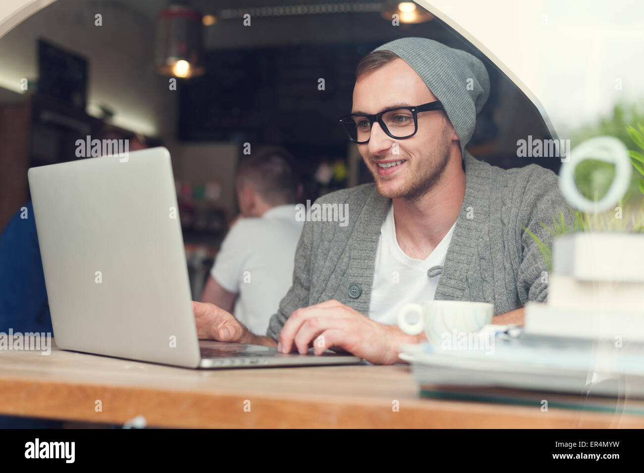 Guapo hipster utilización portátil en el cafe. Cracovia, Polonia Foto de stock