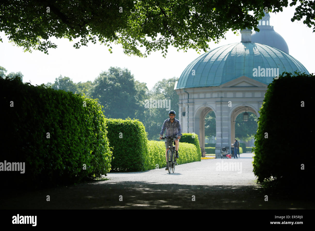 Hombre cabalgando una e-bike a través de Hofgarten, Munich, la Alta Baviera, Alemania Foto de stock