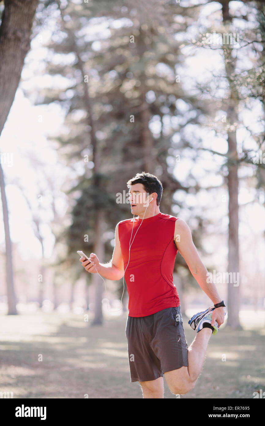 Un hombre joven se prepara para correr en un parque. Foto de stock