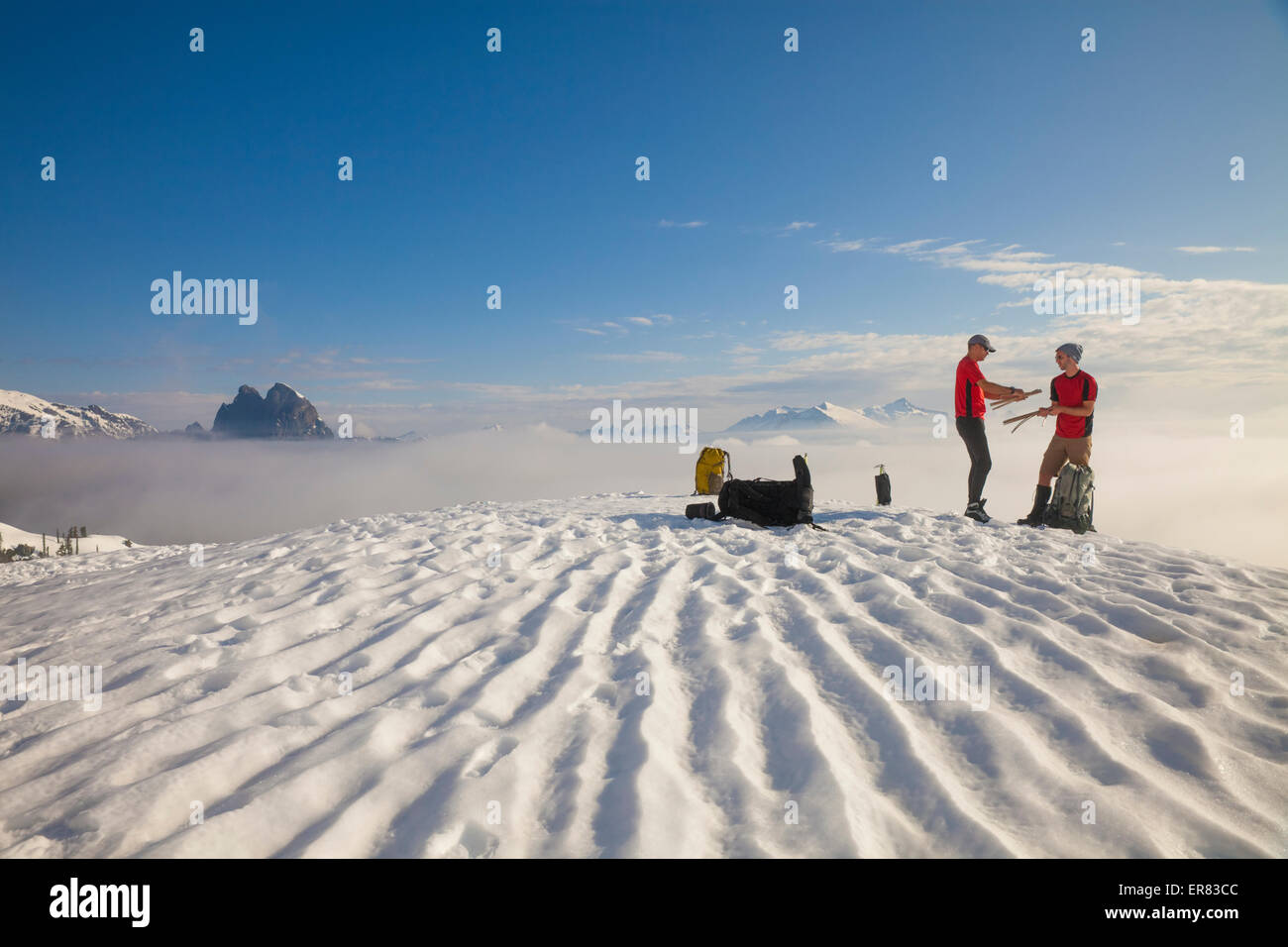Dos escaladores empacar su tienda después de acampar en la nieve en las montañas Foto de stock