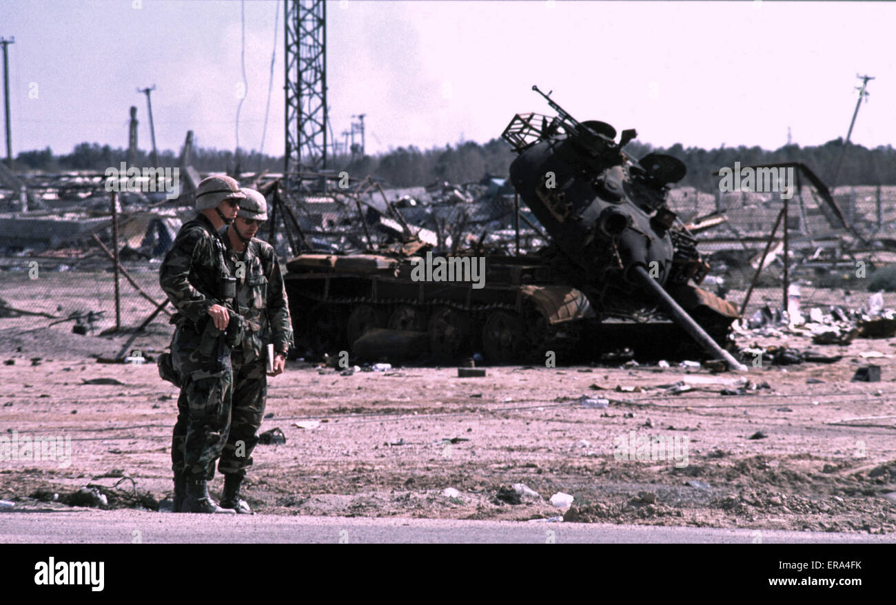 17 de marzo de 1991 soldados del Ejército de los Estados Unidos se encuentran cerca de un tanque iraquí T55 quemado en la frontera con Kuwait, cerca de Safwan, en el sur de Irak. Foto de stock