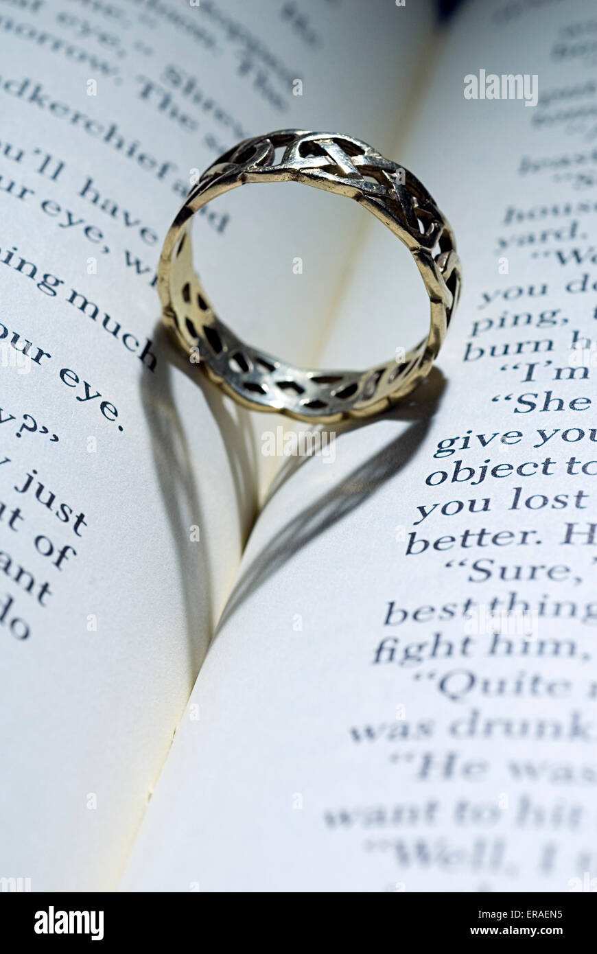 Ring tumbado sobre un libro abierto con sombra con forma de corazón Foto de stock