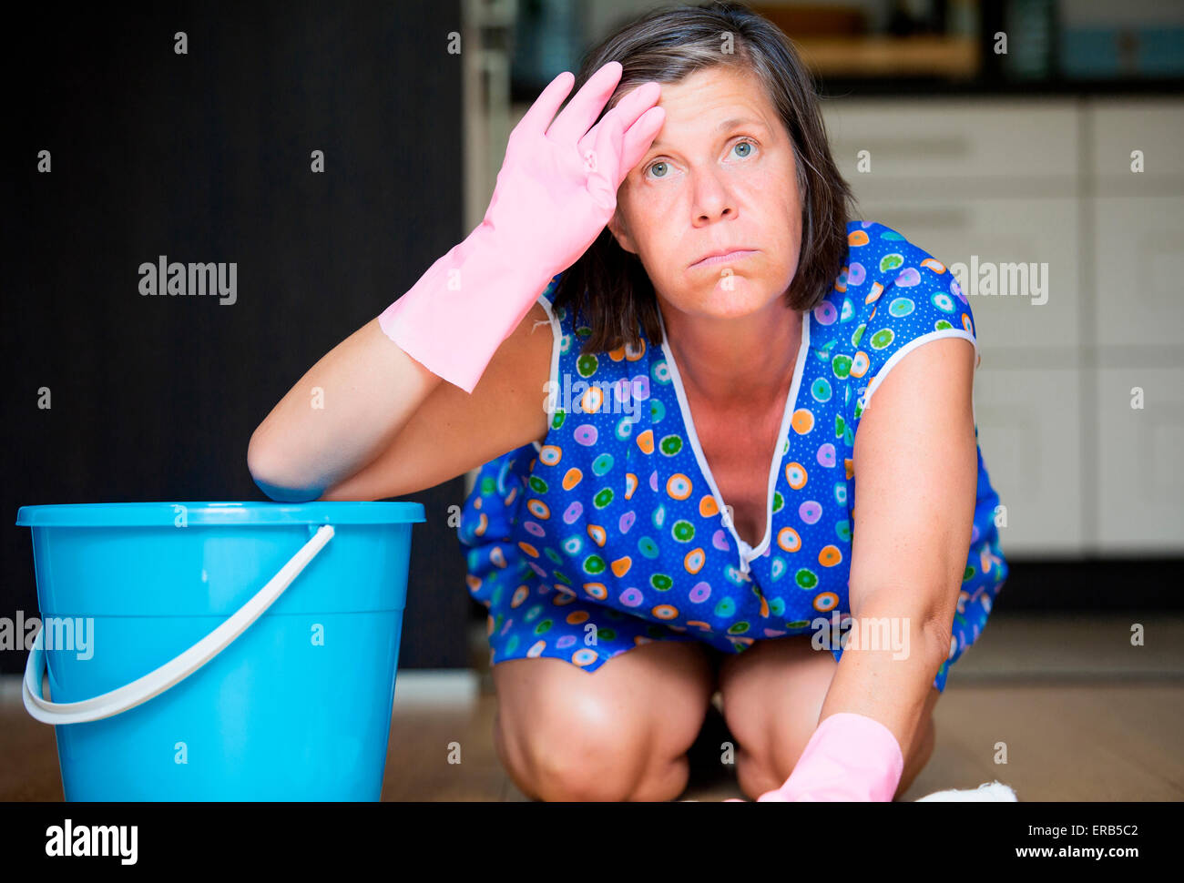 Mujer fregar el piso y mirando agotado Foto de stock